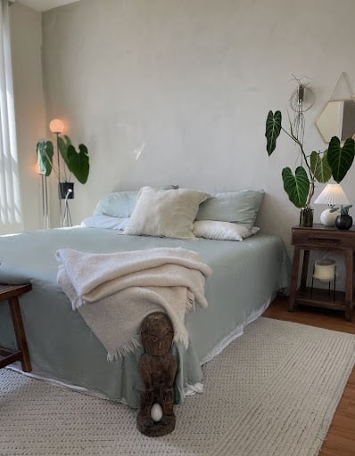 Modern bedroom with neatly styled Derme Home sage green bedding, cozy pillows, and plants
