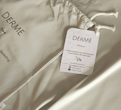 Close-up of Derme Home bedding with eco-friendly fabric tag, emphasizing sustainable and skin-safe materials for acne-prone sleepers.